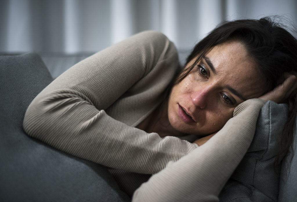 A young brunette woman lying on a couch. She looks unwell