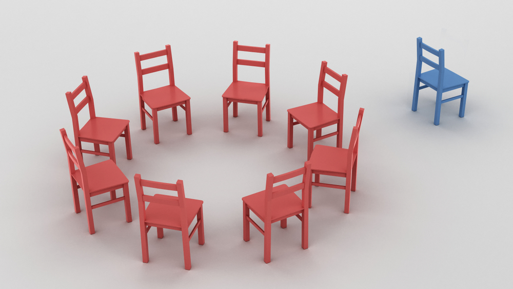 Eight red chairs in a circle with one blue chair on the outside of the circle.