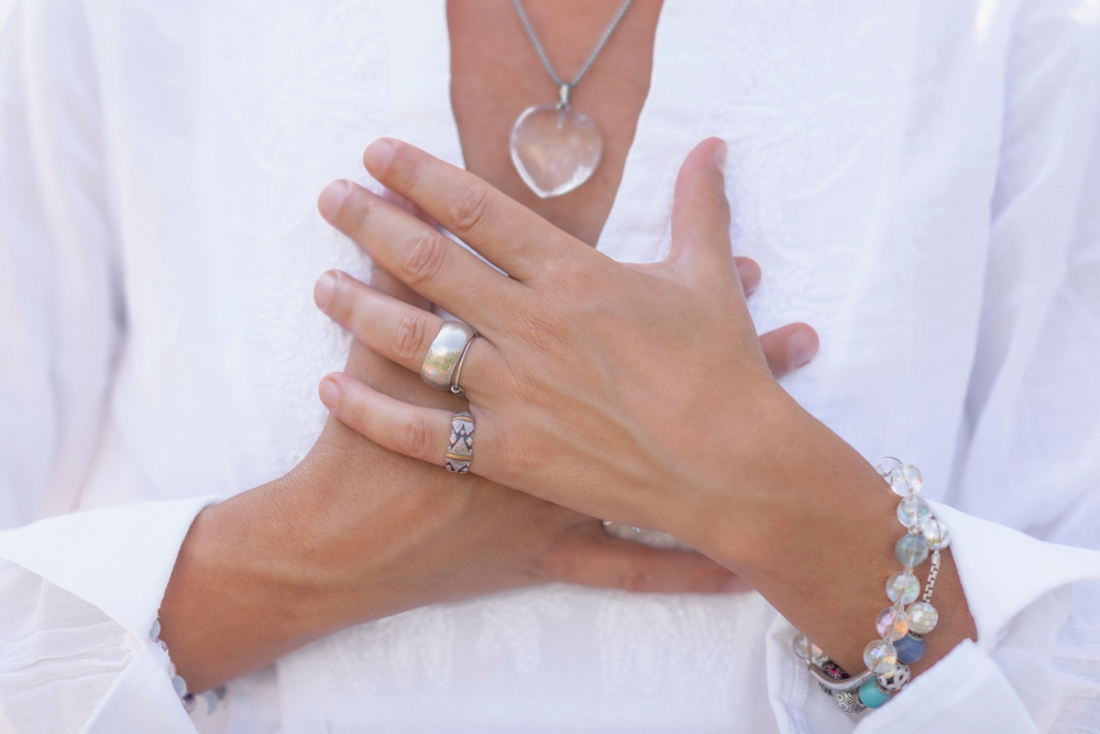 Close up of a female hand. they are clasp together in meditation at her chest.