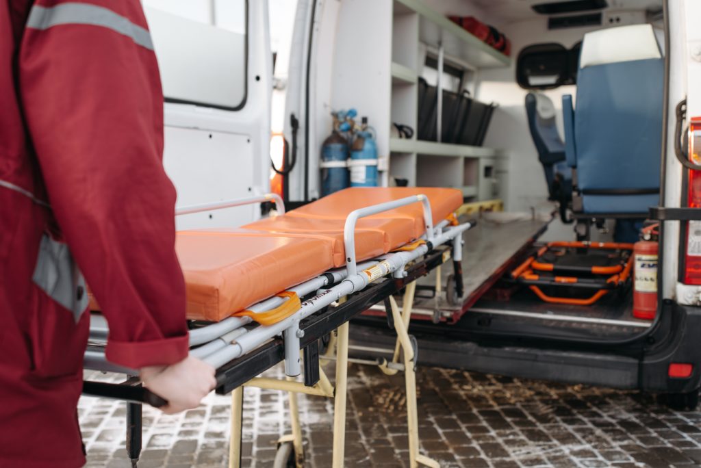 A paramedic loading a bed into the back of an ambulance.