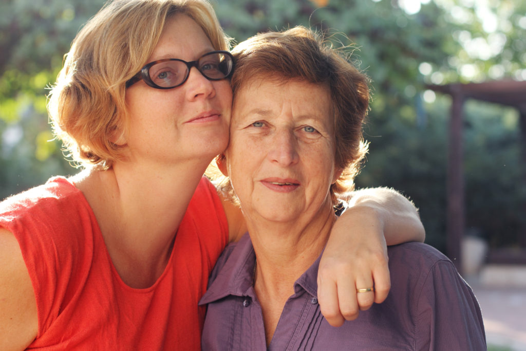 Portrait of an older caucasian woman and her adult daughter hugging