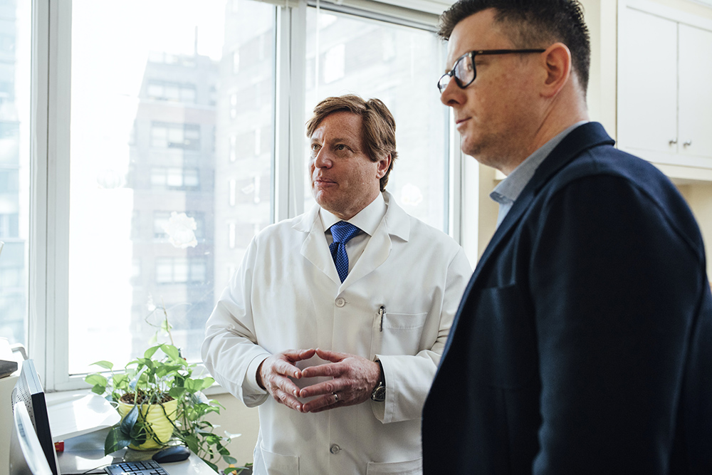 Two caucasian men looking at something while mid conversation.