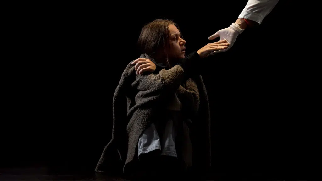 A young female struggling with alcohol withdrawal grasping a doctor’s hand, representing trust and a step toward healing.
