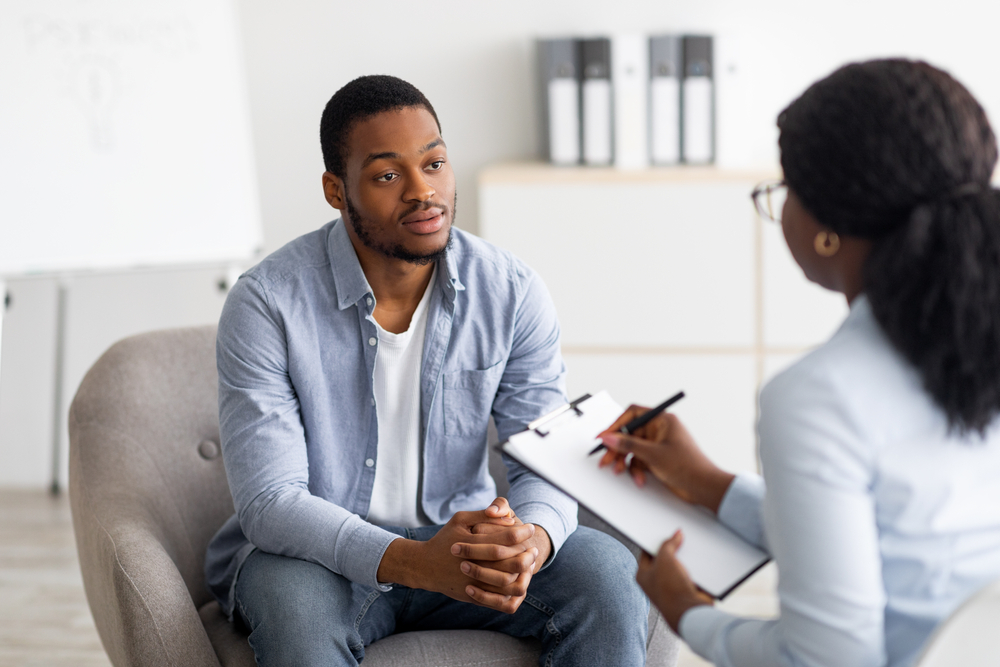 An african-american man talking to an african american woman. She is holding clipboard.