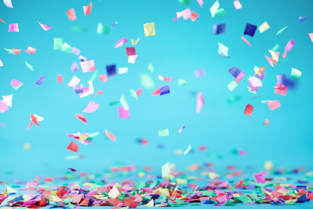 Colourful squares of confetti falling with a blue backdrop