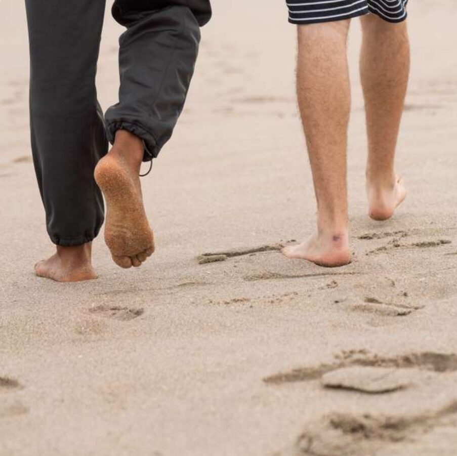 Two individuals walking on the beach, enjoying the sand