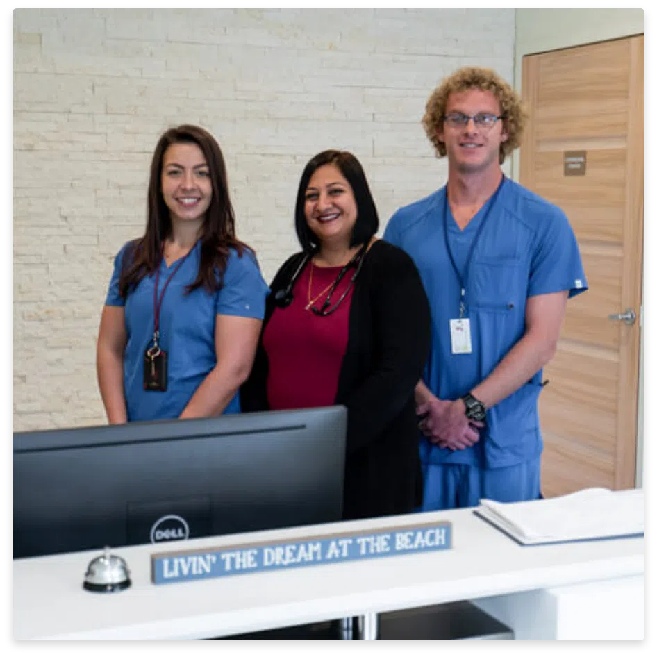 Three healthcare professionals in scrubs at a desk