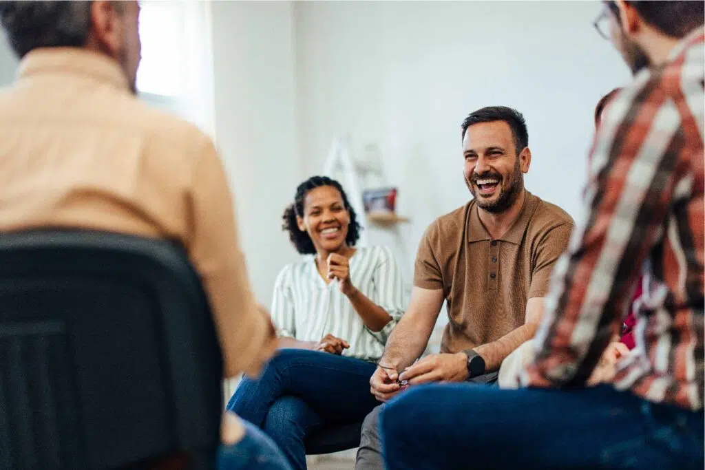 Man laughing with a seated group of people