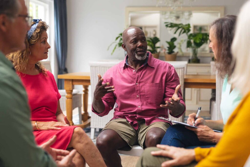 Middle aged man speaking with a seated group of people