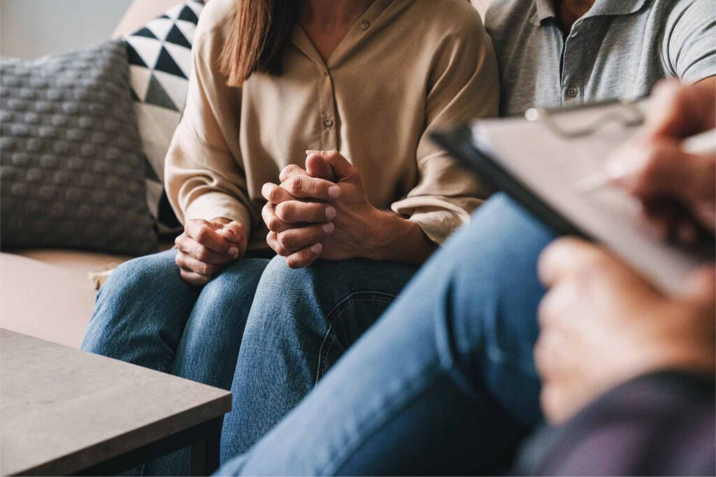 Close up of couple holding hands while sitting on a couch