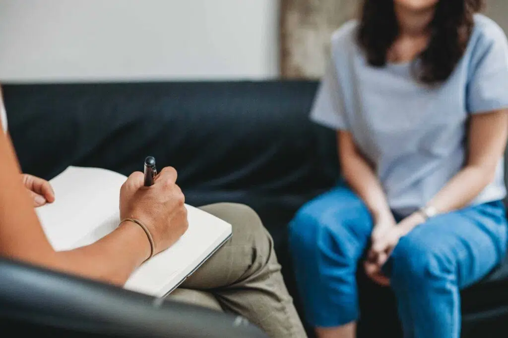 Woman taking notes while another woman speaks on a couch