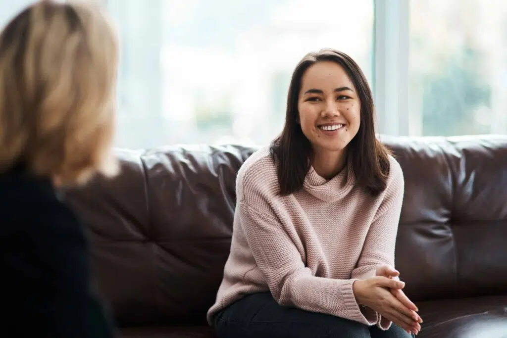 Happy young woman sitting on a couch with therapist