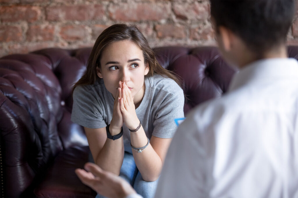 Anxious young woman sitting on couch in therapy