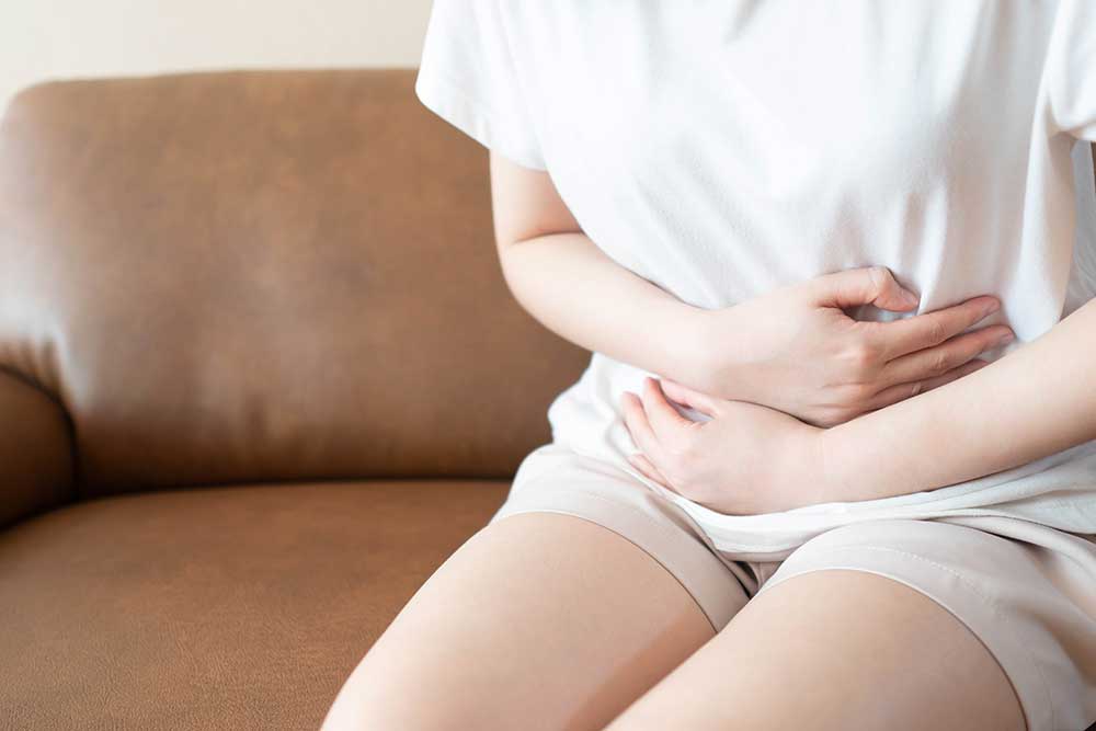 woman sitting on couch holding abdomen