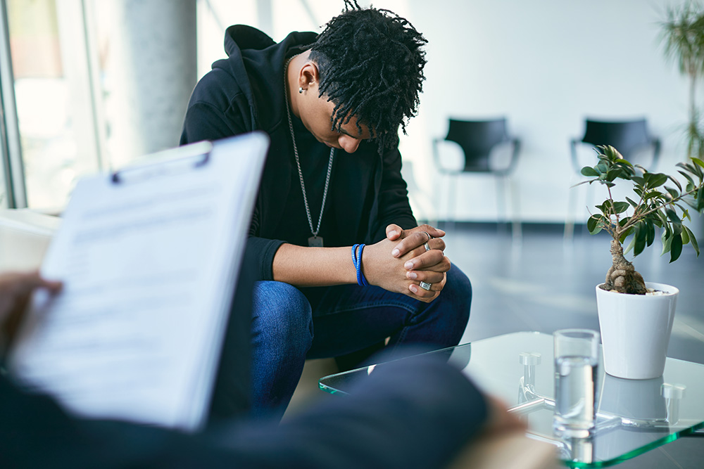 Young man with head down working with therapist
