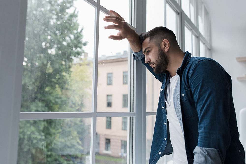 Sad man looking out a window