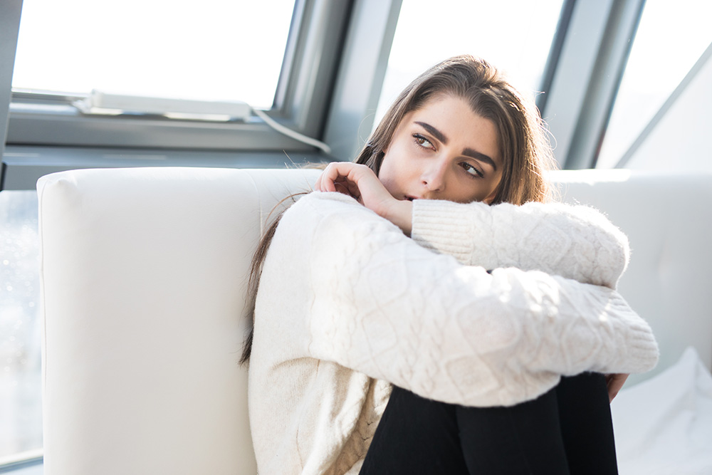 Girl sitting on couch, worried