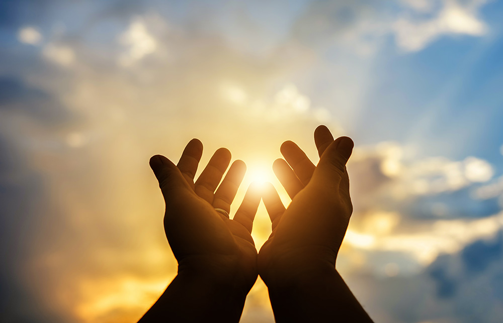 Holding hands up in front of the sun