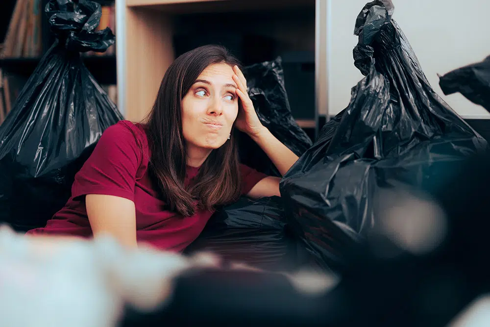 Young woman surrounded by trash bags