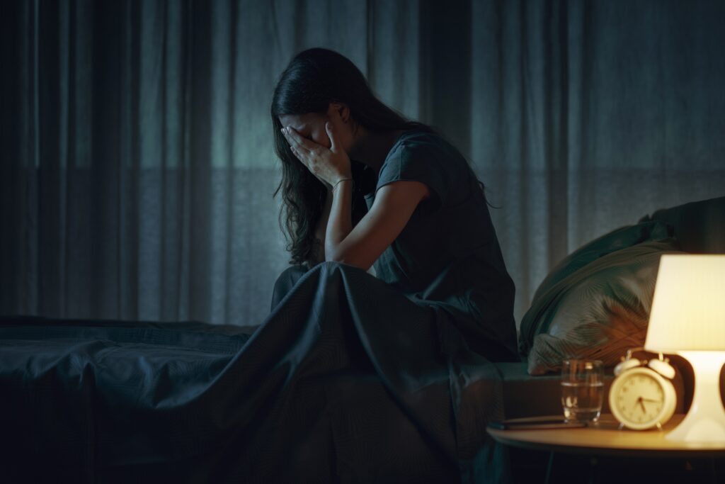 Young woman sitting alone on a bed, illustrating emotional and psychological impact of substance use on the brain.