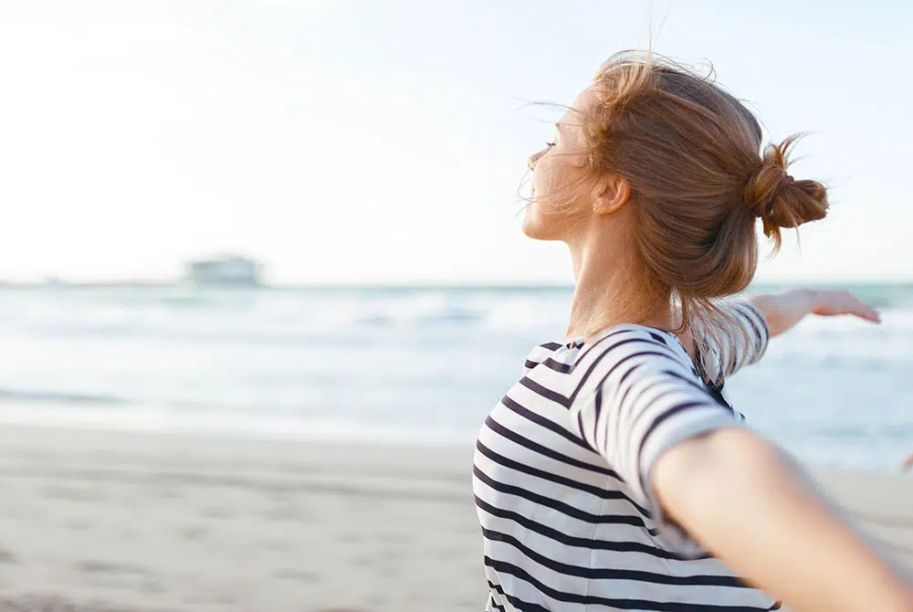 A young woman reflecting outdoors, looking hopefully toward the sky.