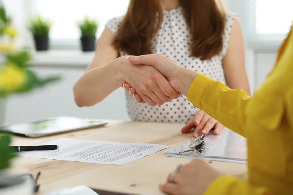 Two women shaking hands, symbolizing trust and collaboration.