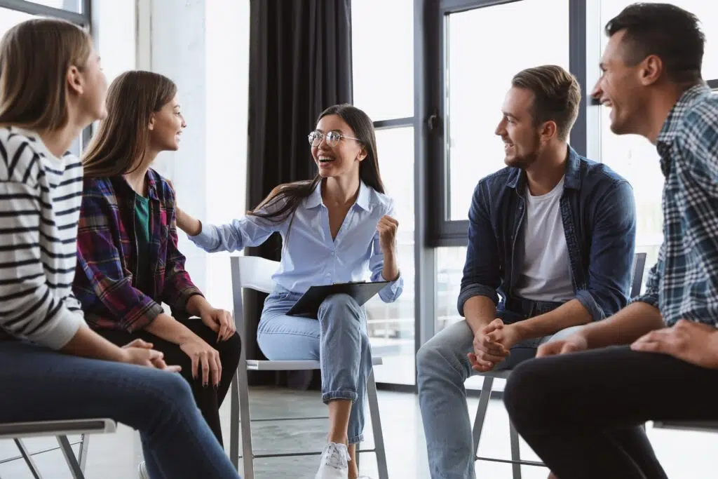 Therapist facilitating a group therapy session with diverse patients sitting in a circle indoors