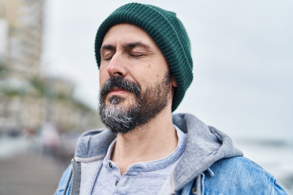 Man with closed eyes breathing deeply outdoors at the seaside.