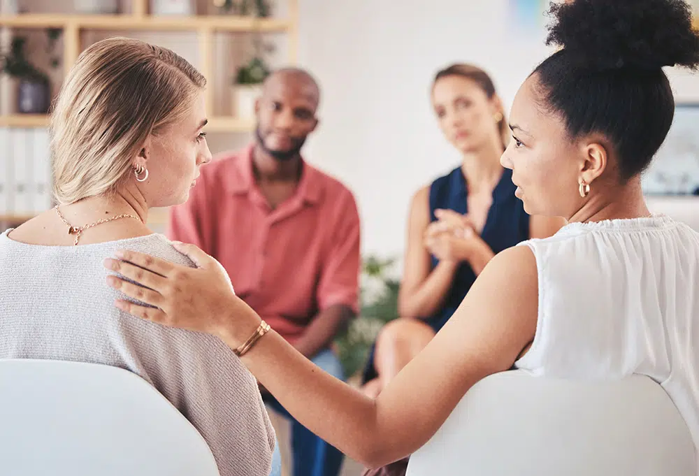A counselor comforts a woman during a detox session.